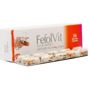 A bottle of Fefol Vit capsules surrounded by green leaves, representing health and vitality.